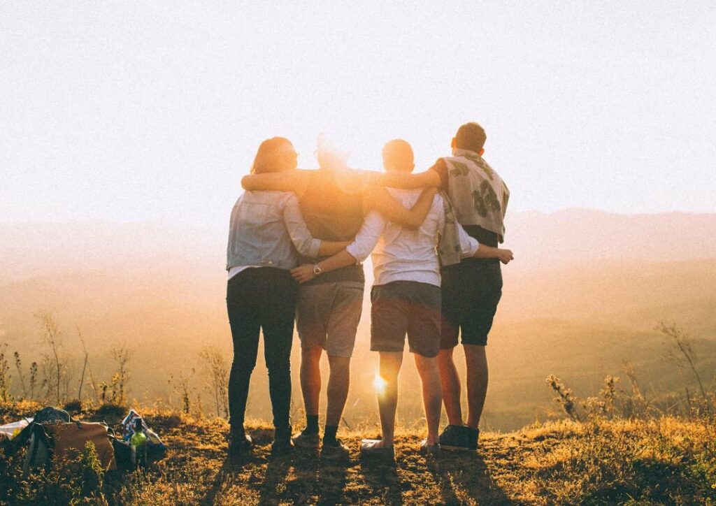 Four friends on a hill, silhouetted against a setting sun. They enjoy the Apex Social Program, as US Care Professionals testify. #Friendship #Sunset