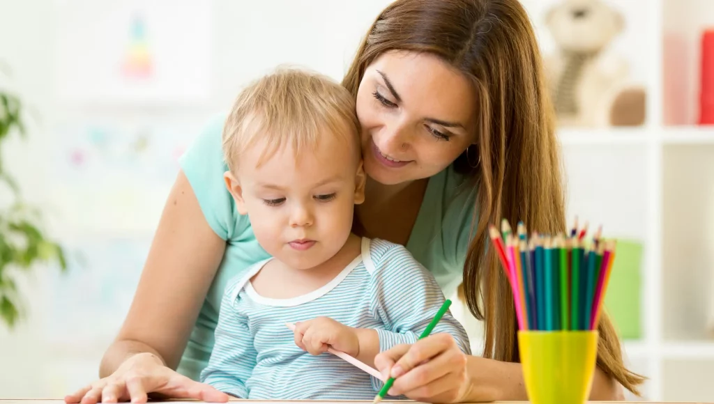 brünette lächelnde Frau und Kind malen mit Stiften