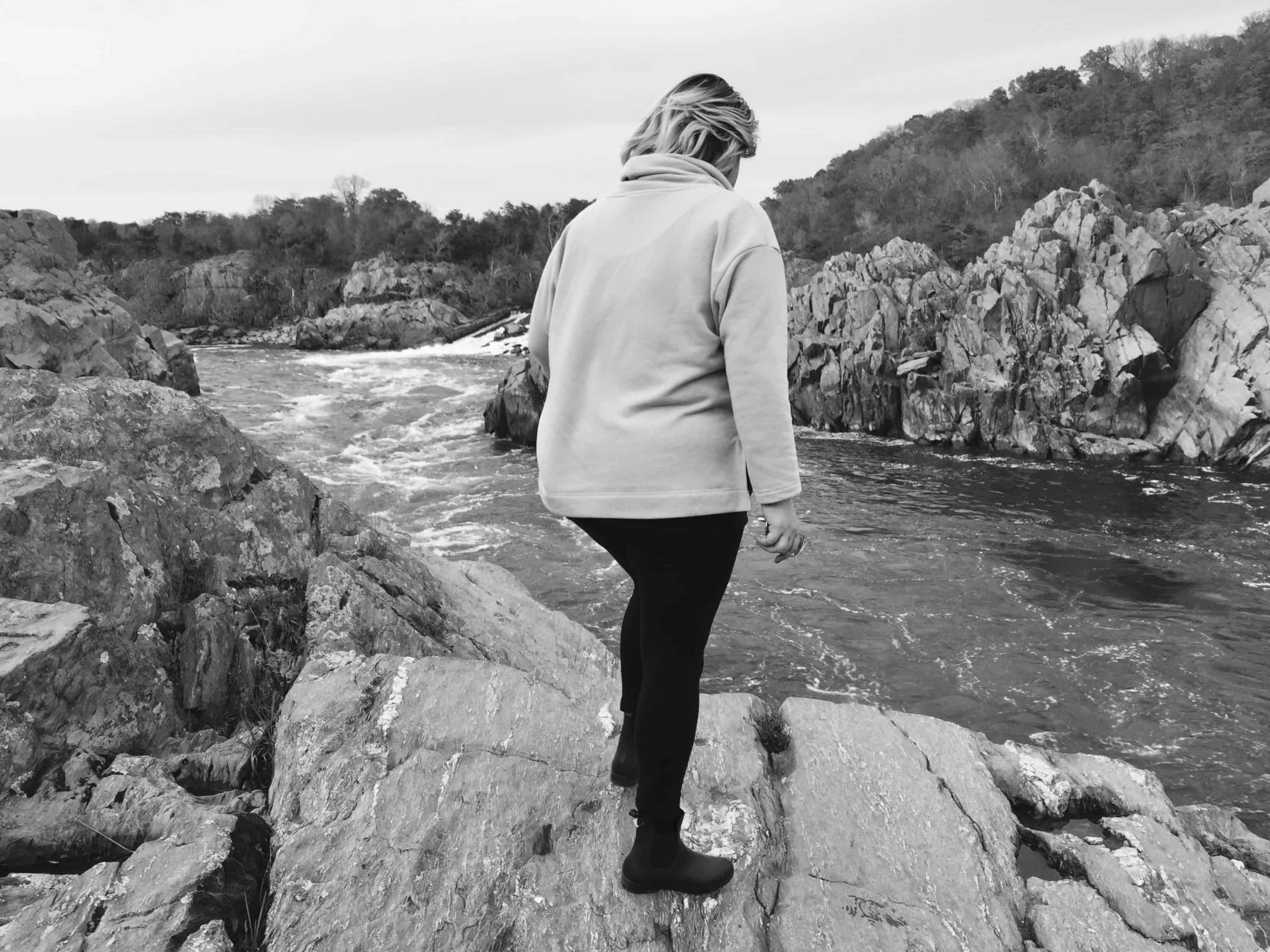 Frau auf steinen an einem Fluss