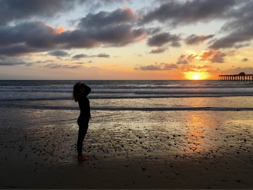 Bild einer Frau am Strand vor dem Sonnenuntergang