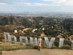 Bild einer Frau am Geländer hinter dem Hollywood Sign