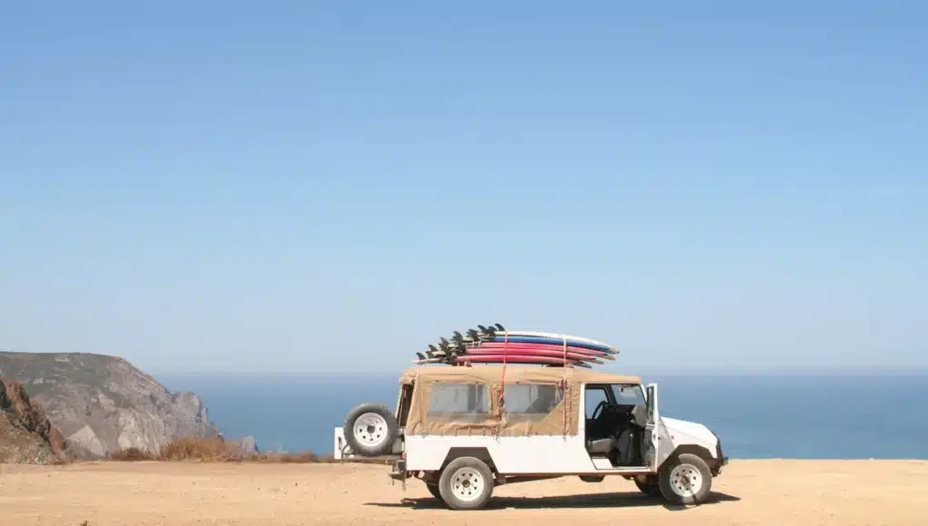 Ein Auto mit mehreren Surfboards auf dem Dach vor einem Meer